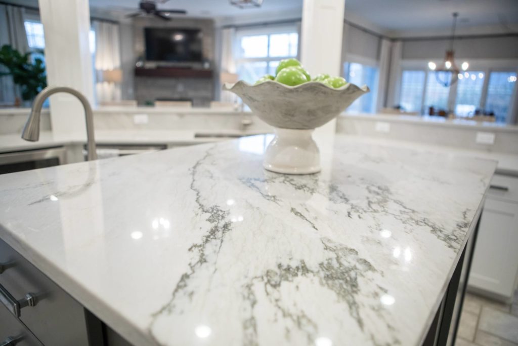 Close up of a floating island with a white marble countertop and a bowl of fruit on top