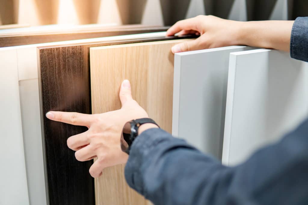 Male hand choosing cabinet panel materials.