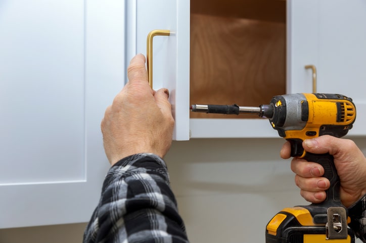The installing a furniture handle process of assembling kitchen cabinet