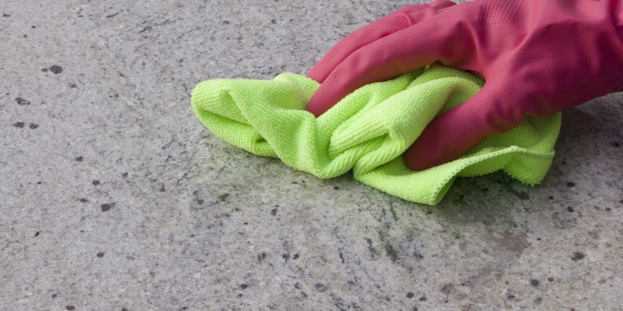 Cleaning a granite kitchen worktop with a rag