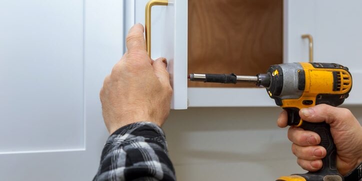 The installing a furniture handle process of assembling kitchen cabinet