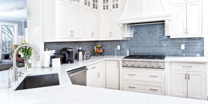 A contemporary home kitchen with stainless steel appliances and painted white cabinets.