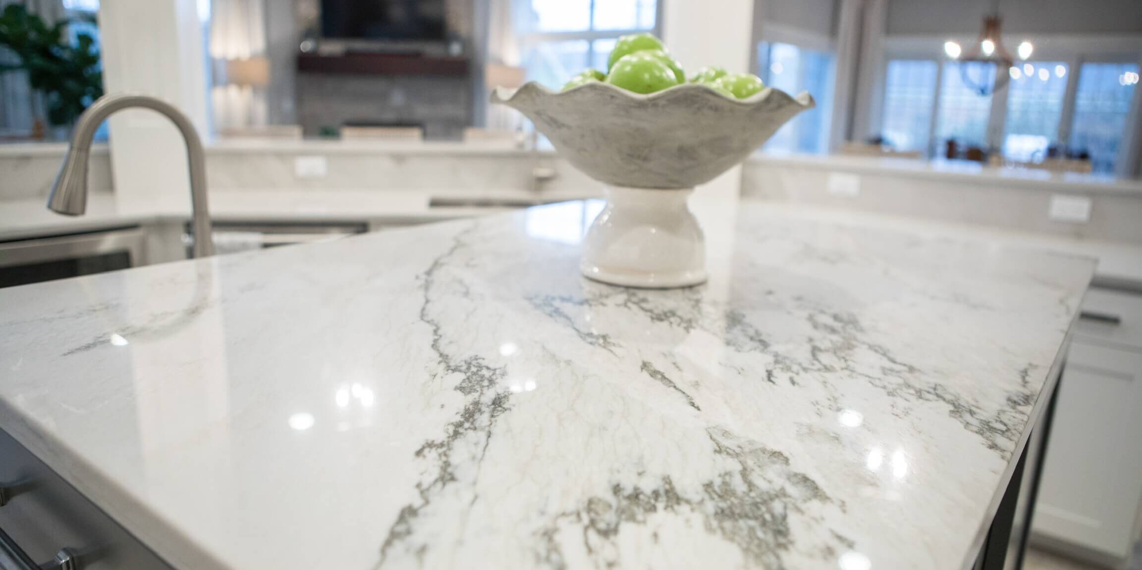 Close up of a floating island with a white marble countertop and a bowl of fruit on top